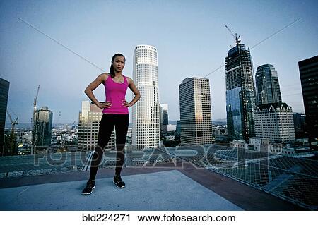 Stock Image - Mixed Race woman standing on urban rooftop. Fotosearch