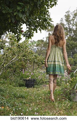 Picture - Mixed race woman talking next to fruit trees. Fotosearch