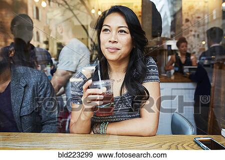 Stock Photo - Mixed Race woman thinking in cafe window. Fotosearch