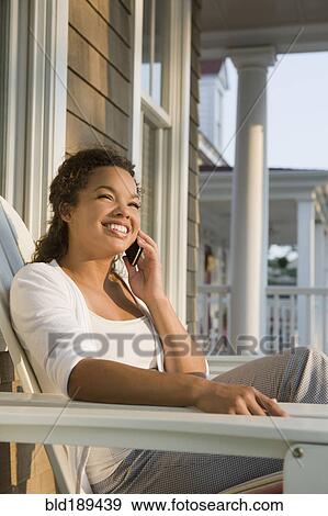 Stock Photo - Mixed race woman using cell phone on porch. Fotosearch