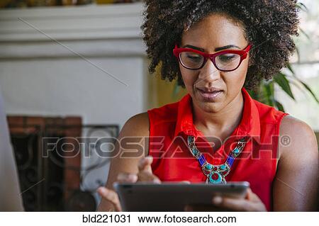 Stock Image - Mixed race woman using digital tablet. Fotosearch