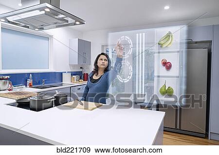 Mixed race woman using holographic screen in kitchen View Large Photo Image Stock Photo - Mixed race woman using holographic screen in kitchen. Fotosearch