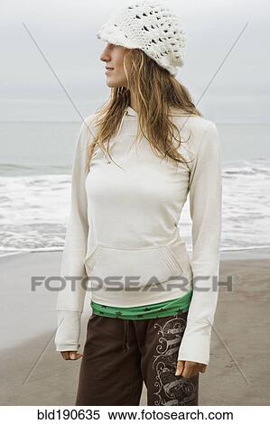Stock Photography - Mixed race woman wearing hat at beach. Fotosearch