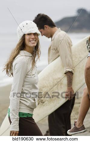Stock Image - Mixed race woman with friends at beach. Fotosearch