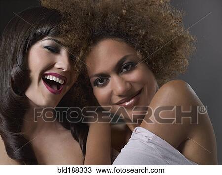 Stock Image - Mixed Race women hugging and laughing. Fotosearch