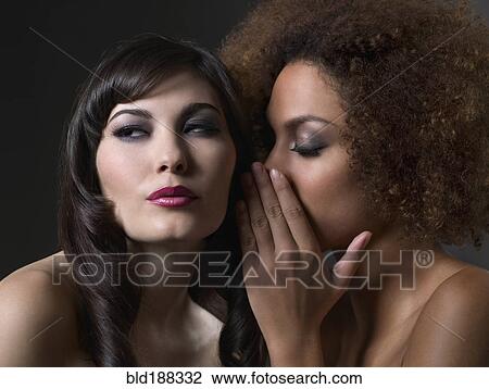 Stock Image - Mixed Race women telling secret. Fotosearch