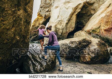 Mother and daughter climbing on beach rocks View Large Photo Image Stock Photo - Mother and daughter climbing on beach rocks. Fotosearch