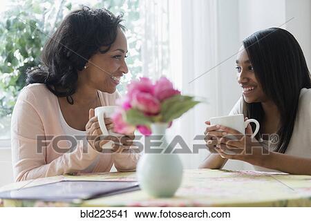 Stock Image - Mother and daughter drinking coffee in restaurant. Fotosearch