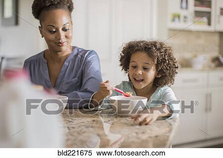 Stock Photography - Mother and daughter eating at table. Fotosearch
