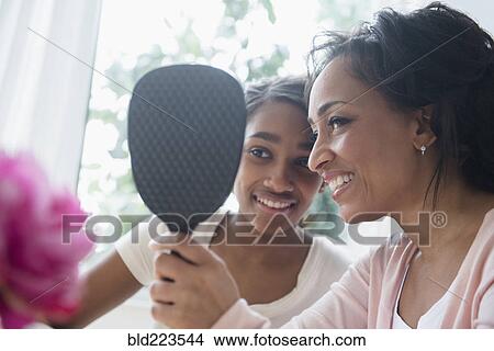 Picture - Mother and daughter looking in handheld mirror. Fotosearch