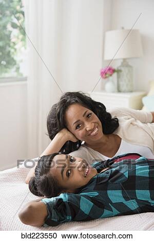Stock Image - Mother and daughter relaxing on bed. Fotosearch