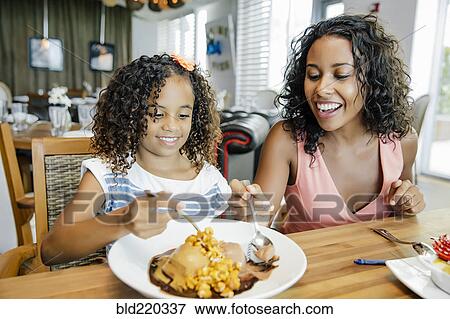 Stock Photo - Mother and daughter sharing dessert in restaurant. Fotosearch