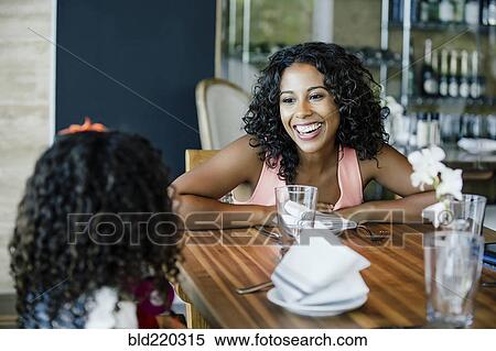 Stock Photography - Mother and daughter talking at restaurant table. Fotosearch