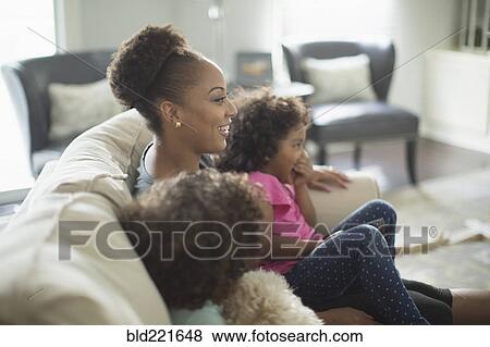 Mother and daughters watching television on sofa View Large Photo Image Stock Photo - Mother and daughters watching television on sofa. Fotosearch