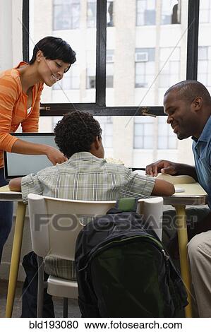 Stock Image - Mother and fathering helping son with homework. Fotosearch