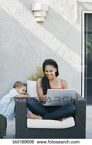 Mother and son looking at laptop on patio View Large Photo Image Stock Photograph - Mother and son looking at laptop on patio. Fotosearch