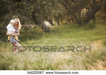 Stock Photo - Mother carrying son in field. Fotosearch