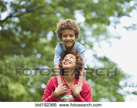 Mother carrying son on her shoulders View Large Photo Image Stock Photograph - Mother carrying son on her shoulders. Fotosearch