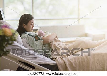 Mother cradling newborn baby in hospital room View Large Photo Image Stock Image - Mother cradling newborn baby in hospital room. Fotosearch