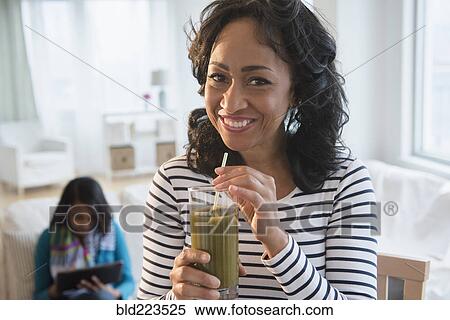 Mother drinking green smoothie while daughter uses digital tablet View Large Photo Image Stock Photography - Mother drinking green smoothie while daughter uses digital tablet. Fotosearch