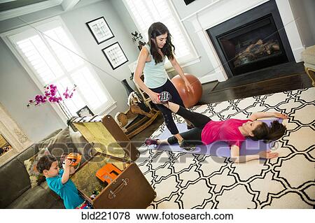 Stock Photo - Mother exercising with trainer in home. Fotosearch