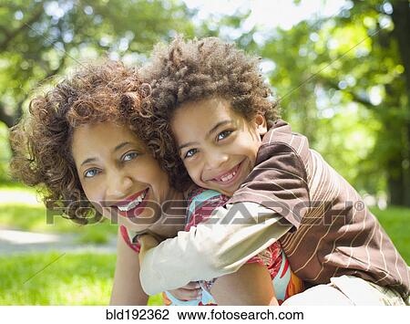 Stock Image - Mother giving son piggy back ride. Fotosearch