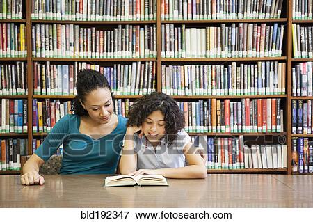 Stock Photo - Mother helping daughter read book in library. Fotosearch