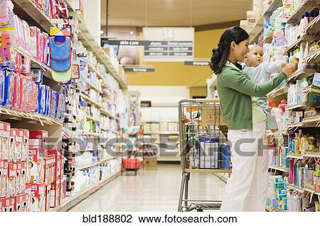 Stock Image - Mother shopping in grocery store with baby. Fotosearch