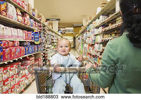 Stock Image - Mother shopping in grocery store with baby. Fotosearch