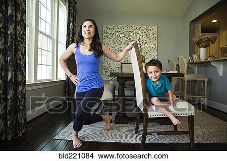 Mother stretching with son in dining room View Large Photo Image Picture - Mother stretching with son in dining room. Fotosearch