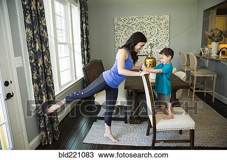Mother stretching with son in dining room View Large Photo Image Stock Image - Mother stretching with son in dining room. Fotosearch