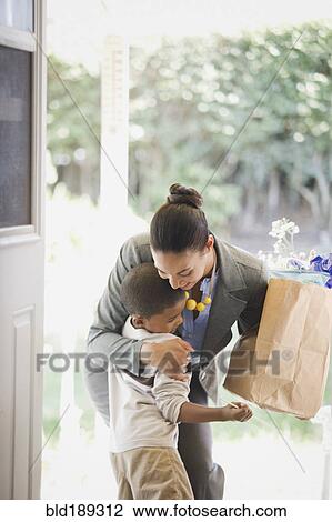 Mother with groceries hugging son View Large Photo Image Stock Image - Mother with groceries hugging son. Fotosearch