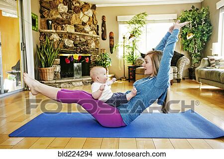 Mother working out on exercise mat with baby in lap View Large Photo Image Picture - Mother working out on exercise mat with baby in lap. Fotosearch