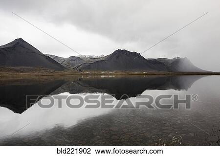 Stock Image - Mountains reflecting in still lake. Fotosearch