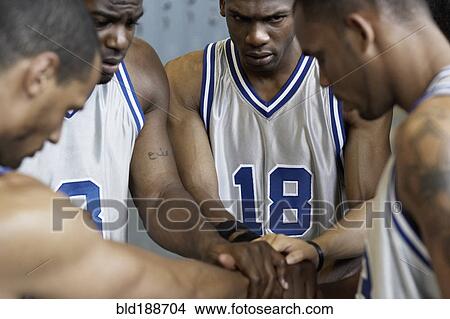 Picture - Multi-ethnic basketball players huddling in locker room. Fotosearch