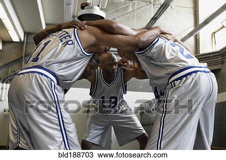Stock Image - Multi-ethnic basketball players huddling in locker room. Fotosearch