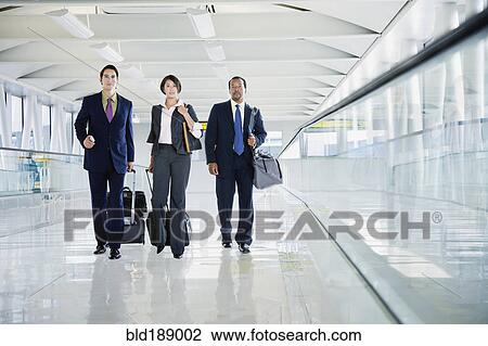Multi-ethnic business people walking in airport View Large Photo Image Stock Image - Multi-ethnic business people walking in airport. Fotosearch