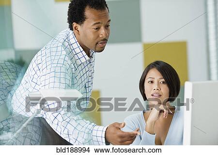 Picture - Multi-ethnic co-workers looking at computer in office. Fotosearch