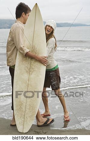 Picture - Multi-ethnic couple holding surfboard. Fotosearch