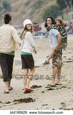 Multi-ethnic friends walking on beach View Large Photo Image Stock Photo - Multi-ethnic friends walking on beach. Fotosearch