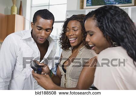 Stock Photo - Multi-ethnic men and women looking at cell phone. Fotosearch