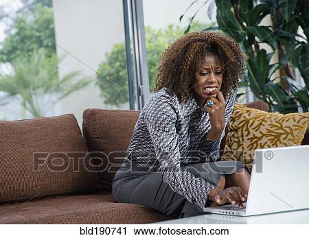 Nervous African woman typing on laptop in living room View Large Photo Image Stock Image - Nervous African woman typing on laptop in living room. Fotosearch