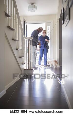 Picture - Nurse helping patient walk with cane. Fotosearch