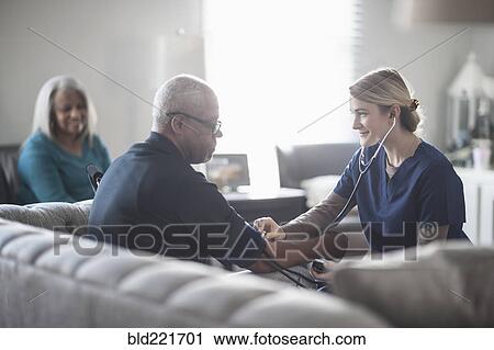 Nurse taking patient blood pressure in living room View Large Photo Image Stock Image - Nurse taking patient blood pressure in living room. Fotosearch
