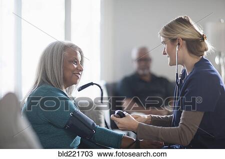 Nurse taking patient blood pressure in living room View Large Photo Image Stock Image - Nurse taking patient blood pressure in living room. Fotosearch