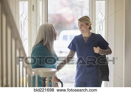 Stock Photo - Nurse talking to patient in front door. Fotosearch