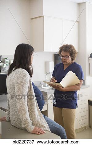 Stock Photo - Nurse talking to pregnant patient in hospital room. Fotosearch