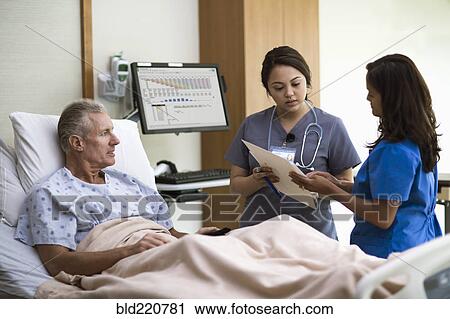 Stock Image - Nurses and patient talking in hospital room. Fotosearch