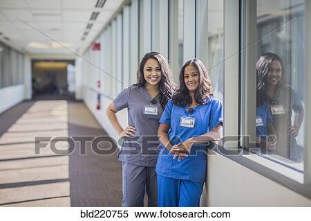 Stock Photography - Nurses smiling in hospital hallway. Fotosearch