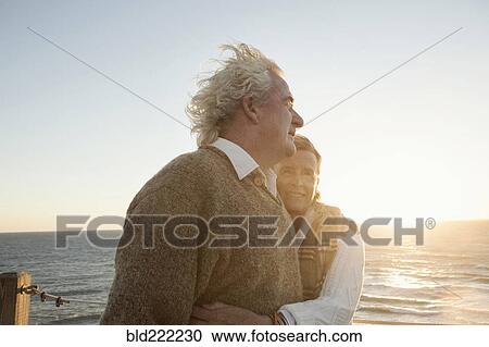Stock Image - Older Caucasian couple hugging outdoors. Fotosearch